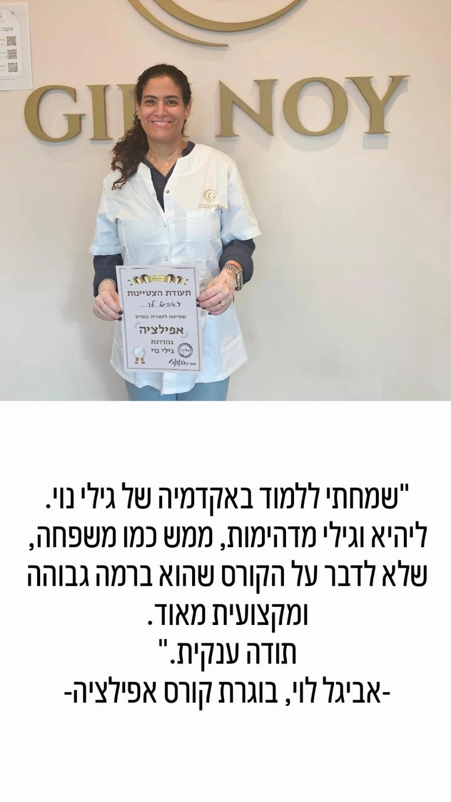 אישה מחייכת לבושה בחלוק לבן מחזיקה תעודה, ועומדת מול שלט שעליו כתוב "גיל נוי".