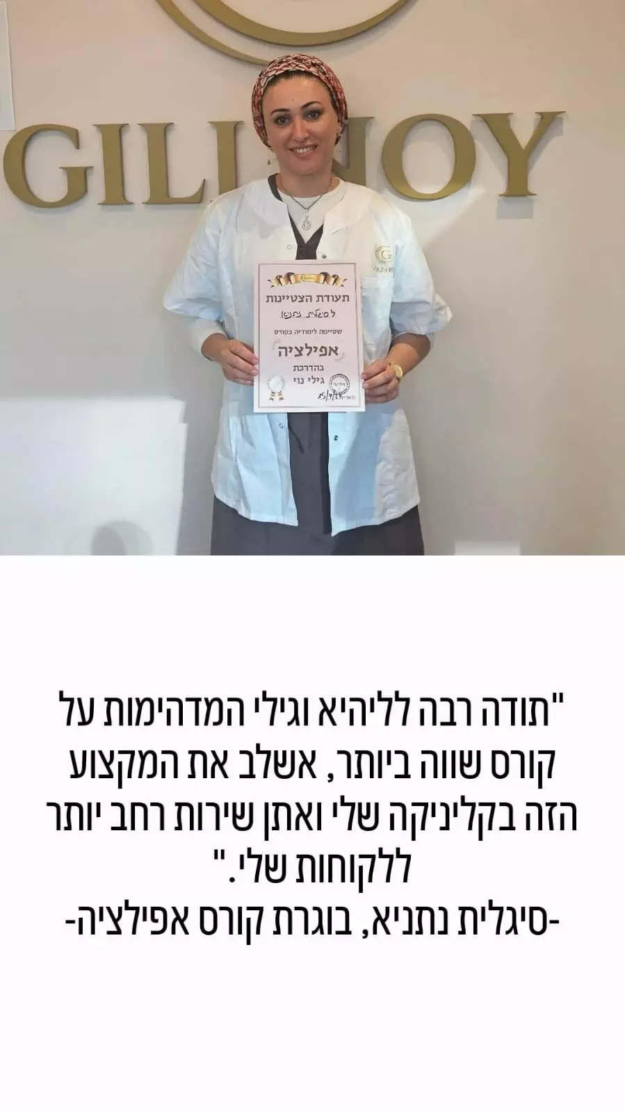 אישה מחייכת לבושה בחלוק מעבדה מחזיקה תעודה, ועומדת מול שלט זהוב שעליו כתוב "GILJOY".