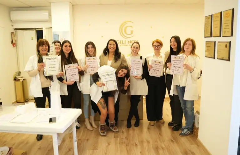 שמונה נשים בתוך חדר, מחייכות ומחזיקות תעודות, מצטלמות לתמונה קבוצתית במשרד מואר היטב.