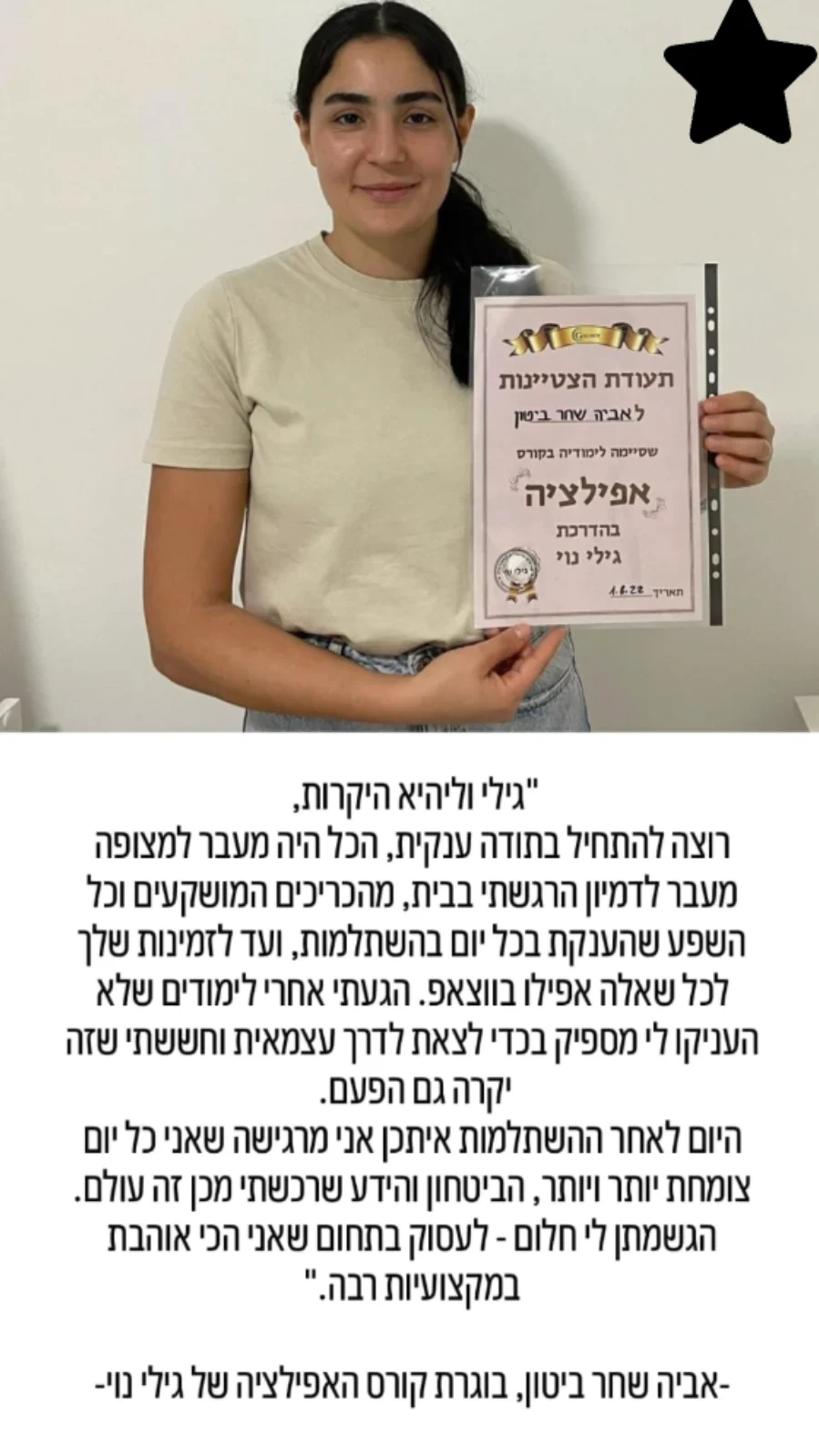 אישה צעירה מחייכת ומחזיקה תעודה בעברית, עומדת על רקע פשוט.